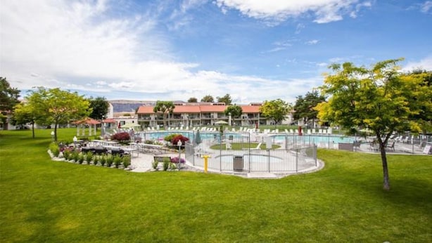 Un hôtel doté d’une piscine, d’un patio couvert et d’une pelouse bien entretenue.