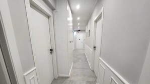 A hallway with white walls and doors, a tiled floor, and recessed lighting. - Belli Suites Vatican Rome Guest House (Rome)
