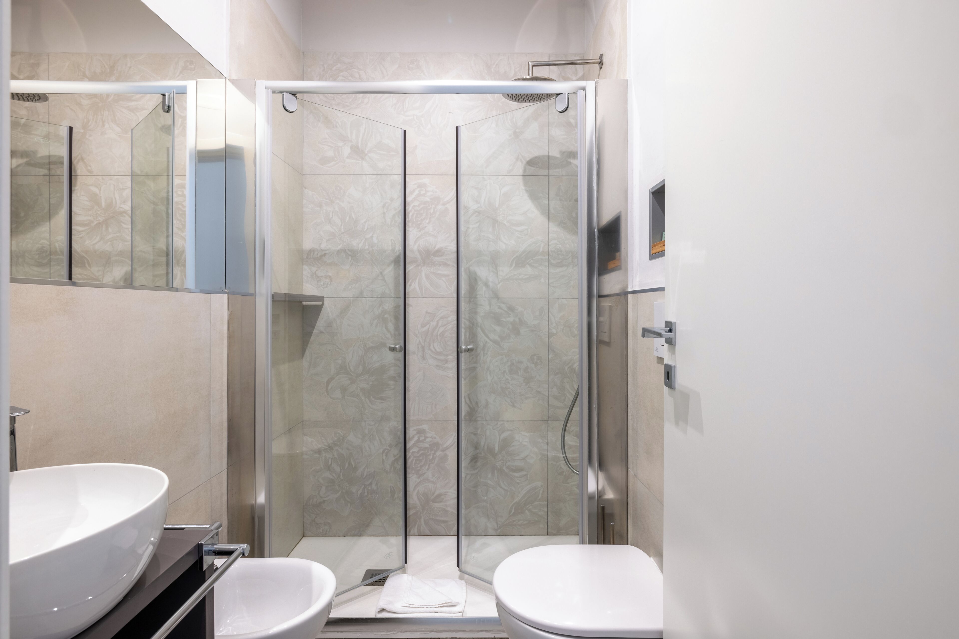 A modern bathroom with a glass-enclosed shower, a white sink, and a toilet.