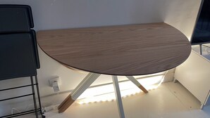 A corner table with a light wood finish, a black metal side table, and a white wall with a power outlet. - Duplexe Paris 6eme (Paris)