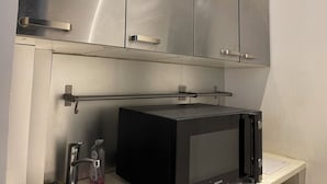 A compact kitchen with stainless steel cabinets, a microwave, and a stainless steel bar. - Duplexe Paris 6eme (Paris)