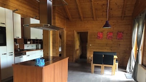 Eine moderne Küche mit Holzausstattung, einer zentralen Kochinsel und einem Essbereich mit Tisch und Stühlen.