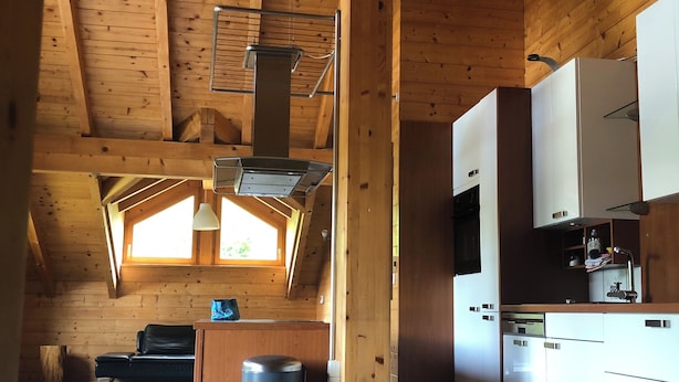 Eine geräumige Küche mit Holzbalken, modernen Geräten und einem großen Fenster für natürliches Licht.