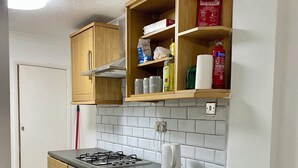 Une cuisine compacte avec des meubles en bois, une cuisinière à gaz, un four encastré et un dosseret carrelé.