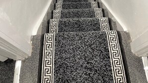 Un escalier recouvert de moquette, orné d’un motif géométrique noir et blanc.