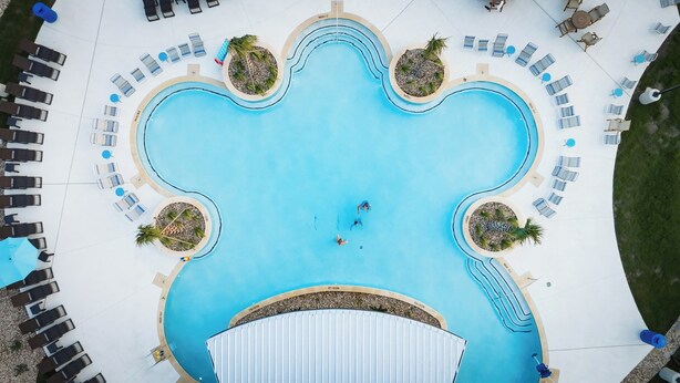 An aerial view of a pool area with multiple lounge chairs and sunbeds arranged around the perimeter. - Camp Landa Resort (New Braunfels)
