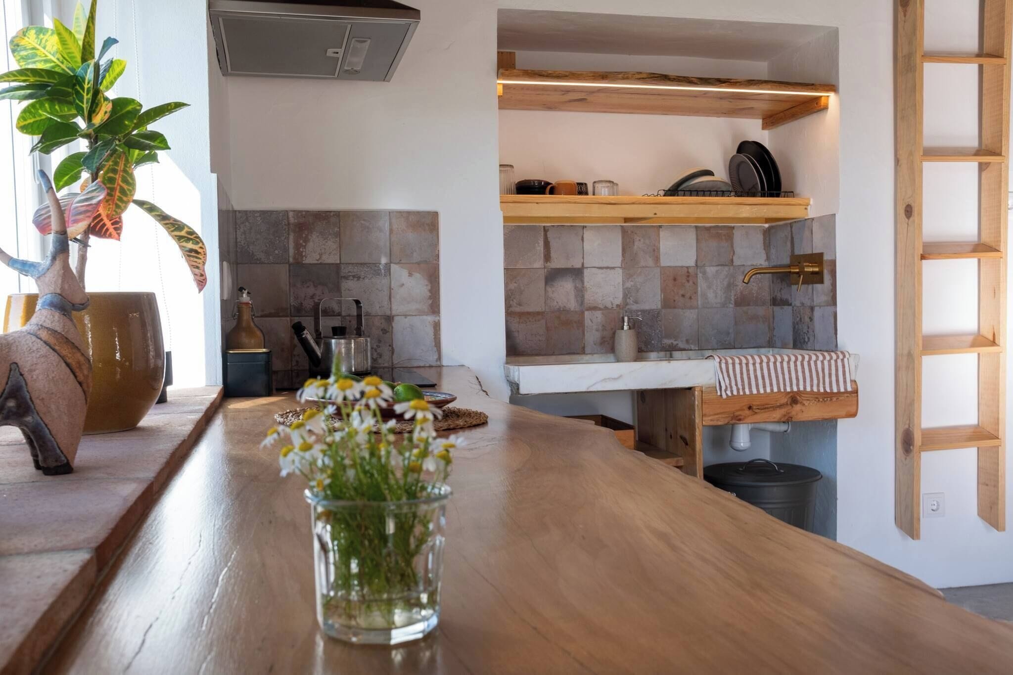 Une cuisine avec un plan de travail en bois, un vase rempli de fleurs et un mur recouvert de carreaux.