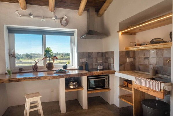 Una cocina con ventana, horno empotrado, encimera de madera y un perchero para toallas.