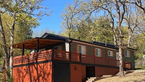A cabin with a wooden deck, a covered porch, and a staircase leading to the entrance. - Kentucky Lodge | Blue Branch | Lake of the Ozarks (Tom Township)