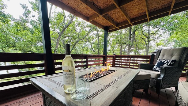 A wooden deck with a glass-top table, a bottle of wine, and glasses. - Kentucky Lodge | Blue Branch | Lake of the Ozarks (Tom Township)