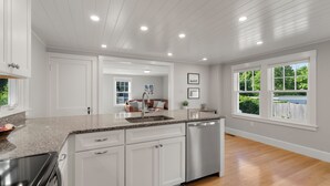 Una cocina moderna con armarios blancos, encimeras de granito y electrodomésticos de acero inoxidable.