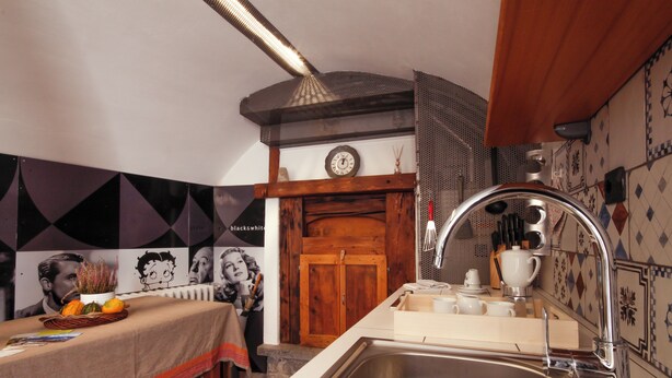 Una cocina con un lavamanos de acero inoxidable, armarios de madera y salpicadero de azulejos.