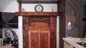 Una puerta de madera con diseño rústico, un reloj de pared encima y una zona de cocina con un fregadero y utensilios.
