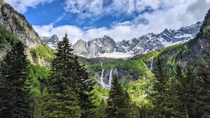 Un paisaje montañoso con bosques densos y numerosas cascadas.