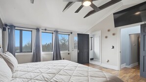 Ein Schlafzimmer mit einem großen Bett, einem Deckenventilator und einer Tür zu einem anderen Raum.