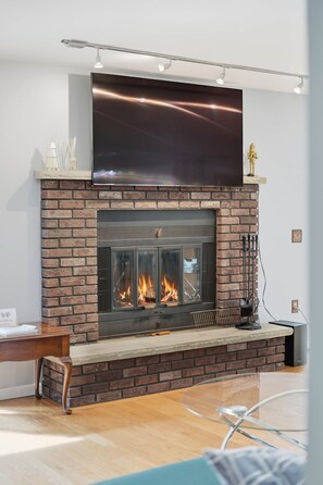 A modern fireplace with a brick surround, a flat-screen TV above it, and a glass table in front.