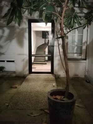 A pathway leading to a staircase, a potted plant, and a building entrance.