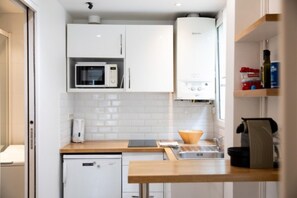 A compact kitchen with white cabinets, a microwave, a dishwasher, and a sink.