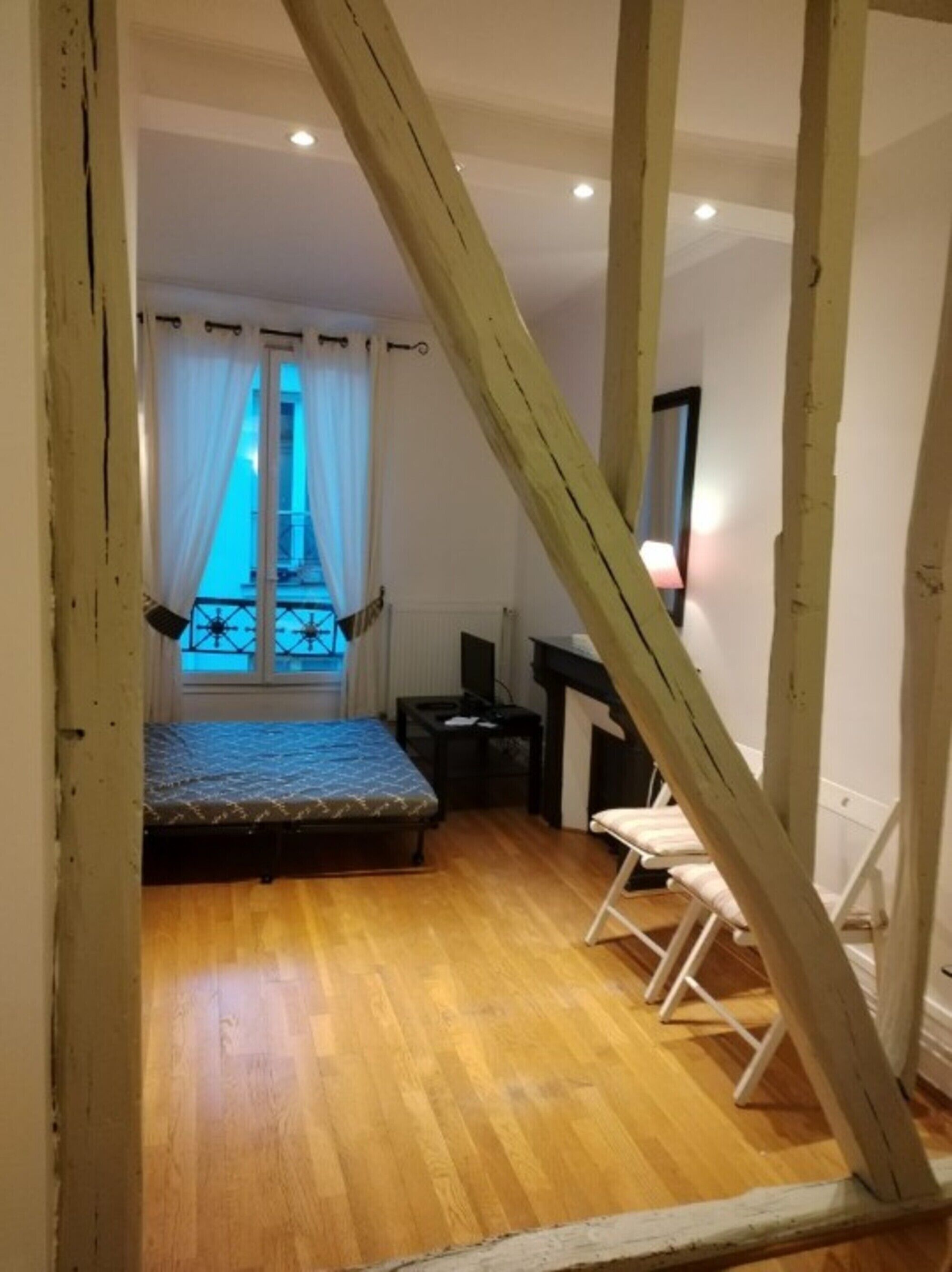 Una habitación con cama, escritorio, silla y ventana con cortinas.