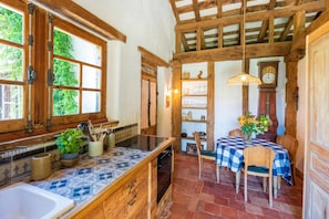A rustic kitchen with a checkered tablecloth, wooden beams, and a clock on the wall. - Holiday Home 'Dependance Avec Jacuzzi' with Terrace, Garden and Wi-Fi (Arcangues)