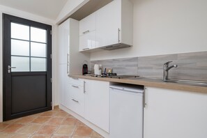 Uma cozinha moderna com armários brancos, uma porta preta e painel de azulejos.