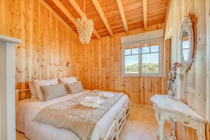 Un dormitorio con paneles de madera, una cama, una mesita de noche, un espejo y una ventana.