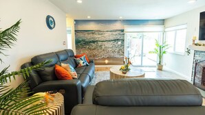 Un salon moderne avec un canapé en cuir, une table basse ronde et une grande fenêtre donnant sur la mer.