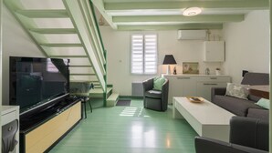 Een moderne woonkamer met een flatscreen televisie, een bank, een salontafel en een trap.