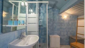 Une salle de bain avec une douche, un lavabo et un miroir.