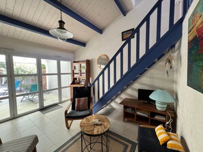 A spacious living area with a staircase, a wooden cabinet, a sofa, a coffee table, and a television.