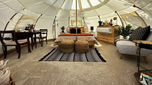 A cozy interior of a tent with a bed, seating area, and a small kitchenette.
