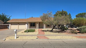 A single-story house with a garage, a small front yard with a tree, and a clear blue sky. - Clean, Comfortable Home Away From Home! (El Paso)