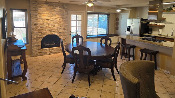 A spacious dining area with a stone fireplace, a large round table, and multiple chairs. - Clean, Comfortable Home Away From Home! (El Paso)