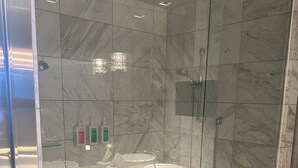 A modern bathroom with a glass-enclosed shower, marble tiles, and a glass shelf. - 1220 square feet strip view with upgraded WiFi  (Las Vegas)