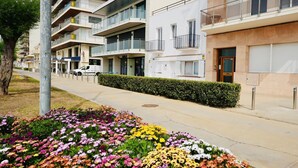 A modern apartment building with balconies, a parking area, and a flower bed in the foreground. - Mundet 1 Baix Mar CostaBravaSi - Sea, beach and AC (Sant Antoni de Calonge)