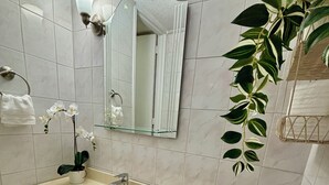 A bathroom with a beige sink, a mirror, and a potted plant.