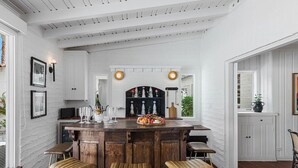 Una cocina con barra de madera, paredes blancas y piso de baldosas.