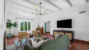 Una sala de estar con un sofá, sillas, una mesa de centro, un televisor y un piano.