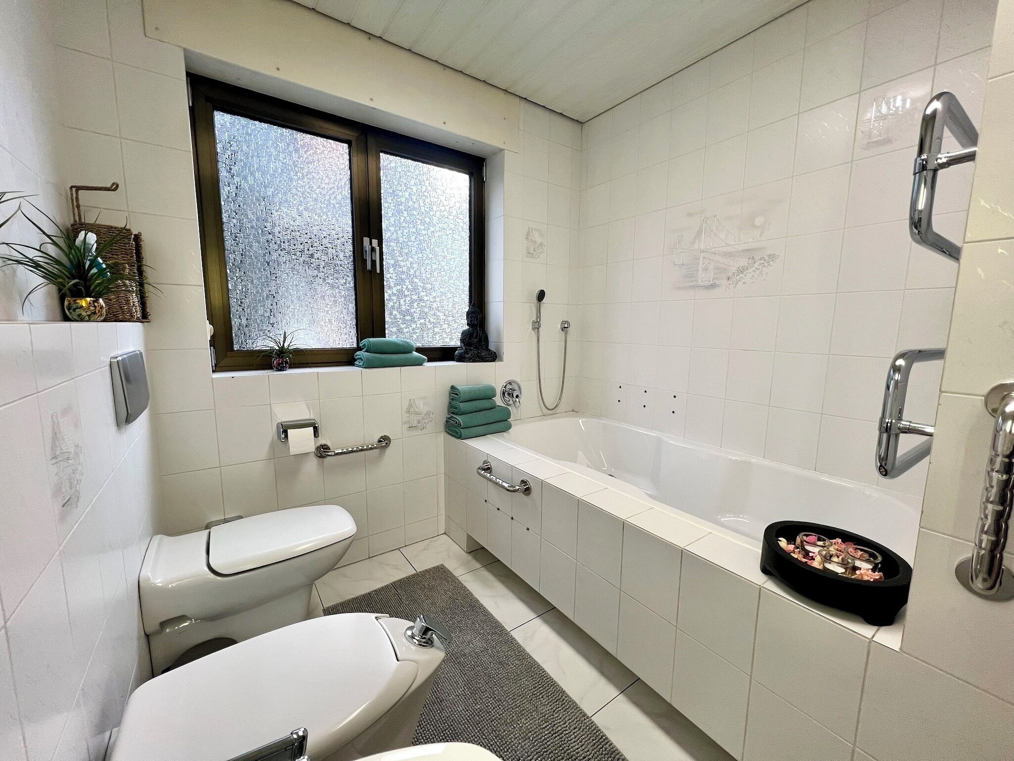 A modern bathroom with a toilet, bidet, and bathtub.