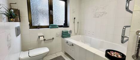 A modern bathroom with a toilet, bidet, and bathtub.