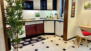 Una cucina moderna con mobili bianchi, pavimento a scacchi bianco e nero, un forno a microonde e un lavandino.