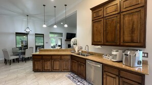 Una cocina moderna con armarios de madera, una isla central, electrodomésticos de acero inoxidable e iluminación colgante.