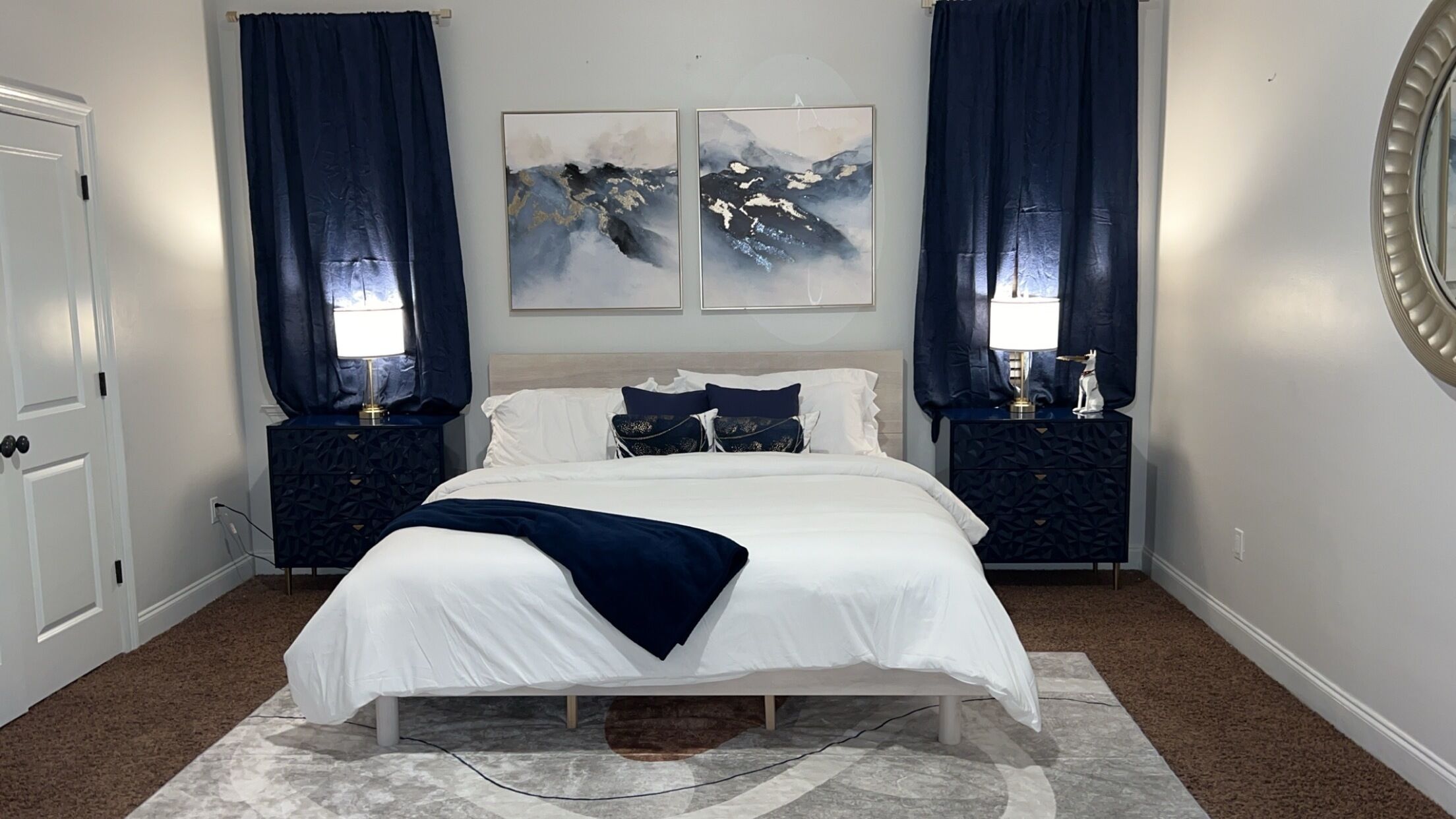 Un dormitorio con una cama grande, dos mesitas de noche, un cabecero y dos cuadros colgados en la pared.
