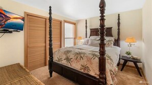 Un dormitorio con cama con dosel, armario de madera y televisor en la pared.