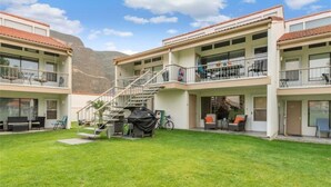 Un motel de dos pisos con un área de estar cubierta al aire libre y una escalera que lleva al piso superior.