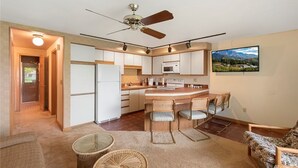 Una cocina compacta con una isla central, ventilador de techo y comedor con sillas.