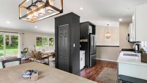 Een moderne keuken met een eethoek, met een grote houten tafel, een ingebouwde oven en een koelkast.