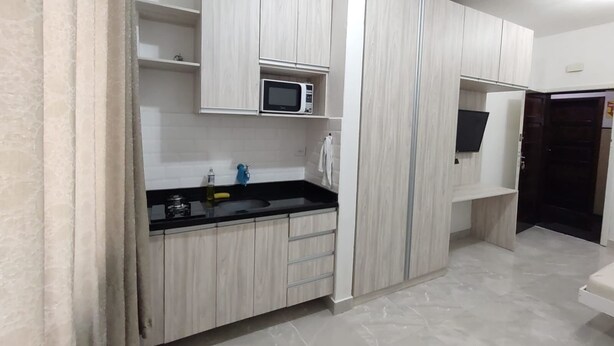A modern kitchen with white cabinetry, a black countertop, a microwave, and a sink.