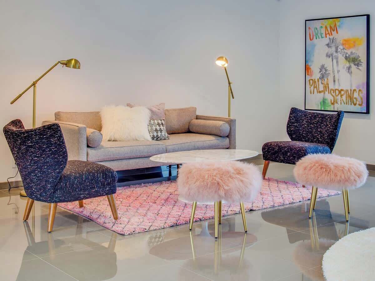 A modern living room with a sofa, two armchairs, a coffee table, and a pink rug.