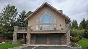 A modern two-story house with a stone facade, large windows, and a garage. - Charming Big Sky meadows house. Trails and Town Center a short walk away. (Big Sky)